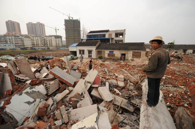 <YONHAP PHOTO-0612> TO GO WITH China-rights-politics-corruption,FEATURE by Neil Connor..This picture taken on March 13, 2013 shows a worker looking out over the rubble where 75-year-old Yao Baohua's house (C-behind) still stands in the city of Changzhou in China's eastern Jiangsu province. The Yao home is the last one standing in the rubble of a vast development site in Changzhou, a Chinese "nail house", the moniker earned for both their physical appearance and their owners' stubborn resistance. AFP PHOTO / Peter PARKS../2013-04-29 13:38:50/ <저작권자 ⓒ 1980-2013 ㈜연합뉴스. 무단 전재 재배포 금지.>
A worker looks out over the rubble where Yao Baohua’s house (center from behind) still stands in the city of Changzhou in China’s eastern Jiangsu province.   AFP-Yonhap News