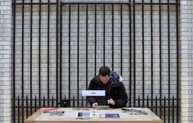 A customer inspects a display model of an Apple Inc. iPad mini at the company’s Covent Garden store in London.   Bloomberg