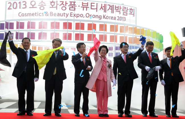 Lee Si-jong (third from right) and Kim Hwa-jung (fourth from right), co-chairs of the Cosmetics & Beauty Expo, and other delegates wave during the opening ceremony for the beauty expo in Osong, North Chungcheong Province, on Friday.   Yonhap News