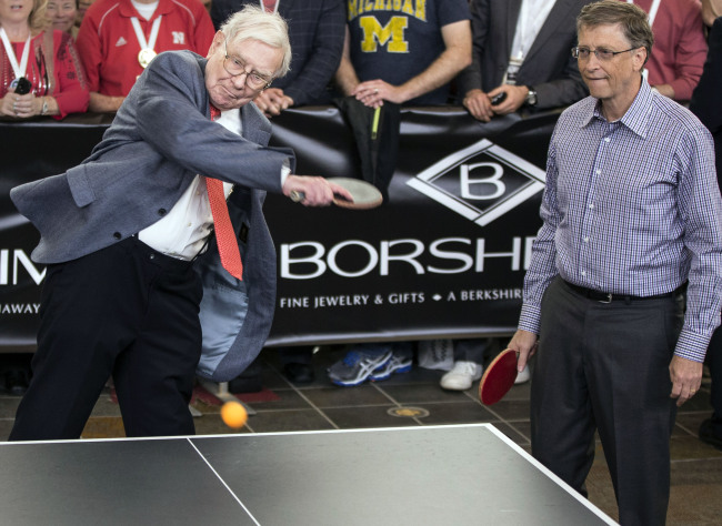 Berkshire Hathaway Chairman and CEO Warren Buffett (left) smashes the ball, as he and Microsoft founder and Berkshire director Bill Gates play table tennis against U.S. national champion Ariel Hsing (unseen), outside Borsheims jewelry store, a Berkshire Hathaway subsidiary, in Omaha, Nebraska, Sunday.    AP-Yonhap News