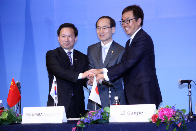 Environment Minister Yoon Seong-kyu (center), his Japanese counterpart Nobuteru Ishihara (right) and Chinese Environmental Protection Vice Minister Li Ganjie join hands after signing a joint communique in Kitakyushu, Japan on Monday.   Yonhap News