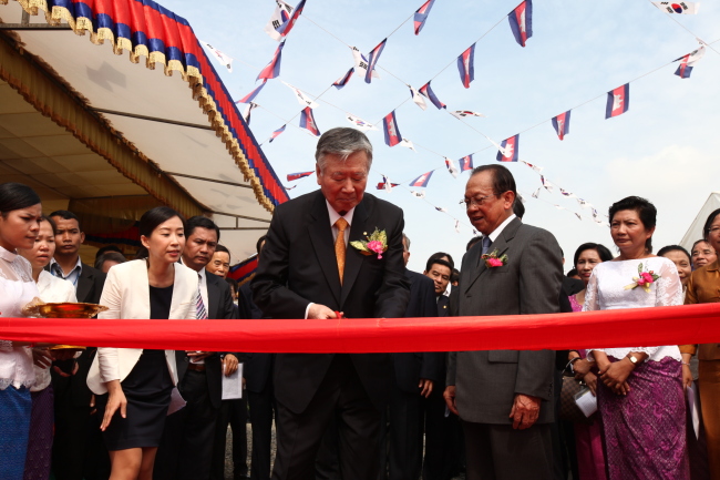 Booyoung Group chairman Lee Joong-keun cuts the ribbon at the groundbreaking ceremony for Booyoung Town in Phnom Penh, Cambodia, Tuesday. Cambodian Land Minister Im Chhun Lim looks on.   Booyoung Group