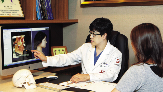 Dr. Kim Tae-gyu (left) shows a 3-D image of a patient’s facial bone structure. (Braun Plastic Surgery)