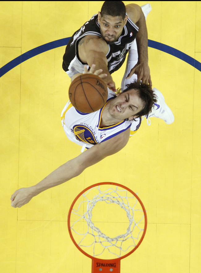 San Antonio Spurs center Tim Duncan (top) and Golden State Warriors center Andrew Bogut battle for a rebound on Sunday.   AP-Yonhap News