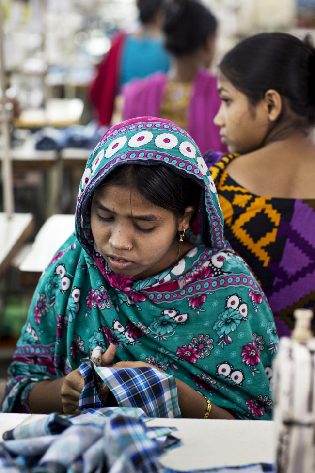 A worker cuts fabric for plaid shirts on the production line of the Fashion Enterprise garment factory in Dhaka, Bangladesh on April 29.   Bloomberg