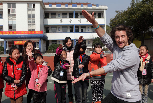 A foreign teacher at Hailiang International School in Zhuji, Zhejiang province, interacts with pupils from a primary school for migrant workers in the city’s Taozhu Street.   China Daily