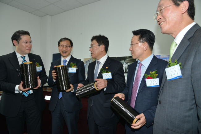 Cho Hyun-sang (left), executive vice president of Hyosung Group, explains carbon fiber to Energy Minister Yoon Sang-jick (third from left) at a ceremony to start commercial production of carbon fiber in Jeonju, North Jeolla Province, Monday. Hyosung Group