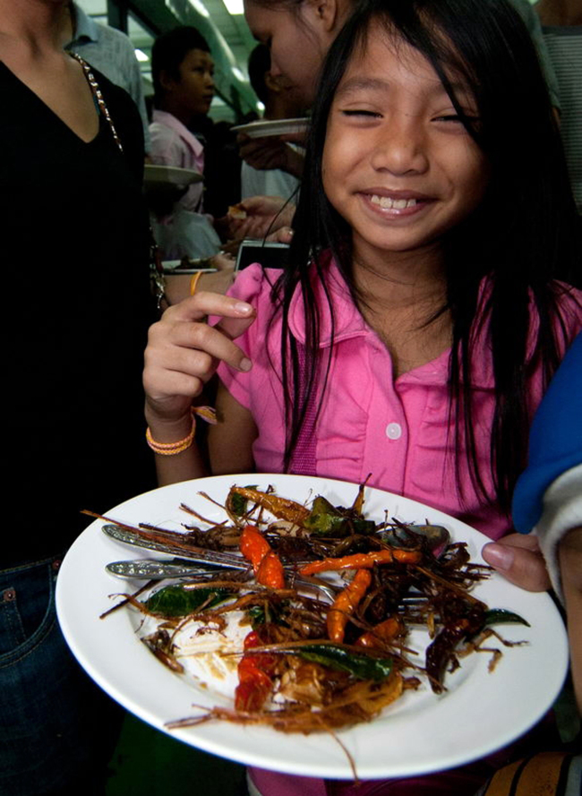 A woman holds a plate with insects during an insect cuisine competition in Laos.   AP-Yonhap News