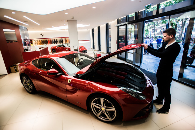 An employee lifts the hood of a Ferrari F12 Berlinetta sports car in the showroom of an automobile dealership in Budapest, Hungary, Wednesday.   Bloomberg