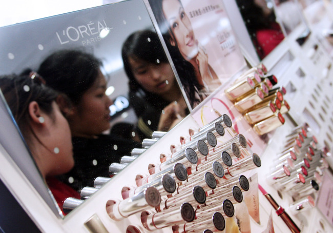 Young Chinese women try out the testers at a L’ Oreal SA cosmetics counter at a shopping mall in Beijing.   Bloomberg