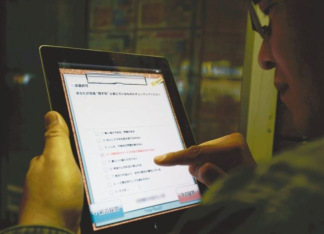 A man answers a DPJ survey on an iPad.   The Japan News