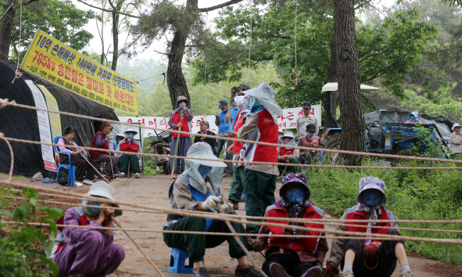 Residents opposing the construction of power transmission towers barricade the path to a construction site in Miryang, South Gyeongsang Province on Monday.   Yonhap News
