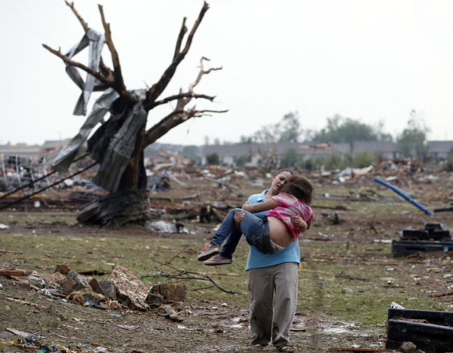 <YONHAP PHOTO-0541> CORRECTS TORNADO MEASUREMENT TO NUMBER REPORTED BY THE NATIONAL WEATHER SERVICE - A woman carries a child through a field near the collapsed Plaza Towers Elementary School in Moore, Okla., Monday, May 20, 2013. A tornado as much as half a mile wide with winds up to 200 mph roared through the Oklahoma City suburbs Monday, flattening entire neighborhoods, setting buildings on fire and landing a direct blow on an elementary school. (AP Photo Sue Ogrocki)/2013-05-21 10:30:16/ <저작권자 ⓒ 1980-2013 ㈜연합뉴스. 무단 전재 재배포 금지.>
A woman carries a child through a field near the collapsed Plaza Towers Elementary School in Moore, Oklahoma, Monday.   AP-Yonhap News