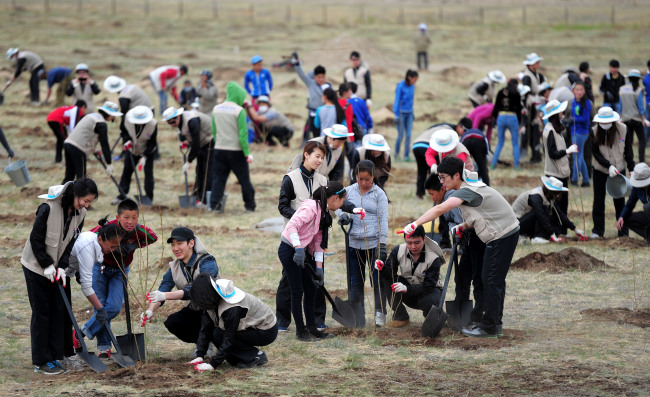 Korean Air employees and Mongolian children plant trees in the Baganor Desert near Ulan Bator, Mongolia, on Wednesday. Korean Air has cultivated the Korean Air Forest in the desert since 2004 when it launched the Global Planting Project.   Yonhap News