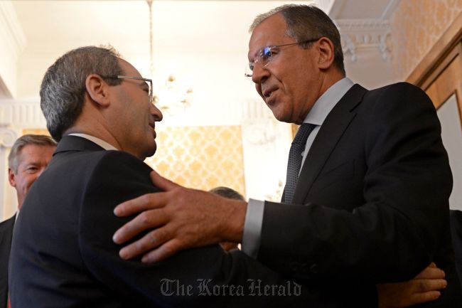 Russian Foreign Minister Sergei Lavrov (right) greets Syrian Deputy Foreign Minister Faisal Muqdad in Moscow on Wednesday. (AFP-Yonhap News)