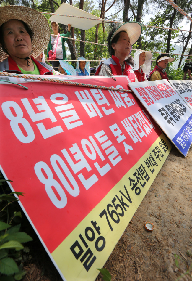 Residents stage a sit-in against the construction of high-voltage transmission towers in Miryang, South Gyeongsang Province, Friday.   Yonhap News