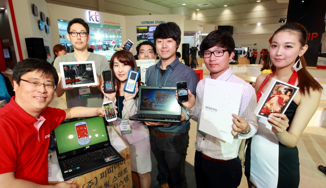 Employees at KT Corp.’s partner companies pose with their products at the World IT Show 2013 held this month.   KT Corp.