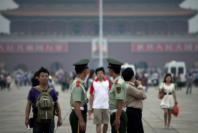 Chinese paramilitary policemen monitor visitors as they stand guard in Tiananmen Square on the 24th anniversary of the deadly 1989 crackdown on pro-democracy protesters in Beijing on Tuesday.   AP-Yonhap News