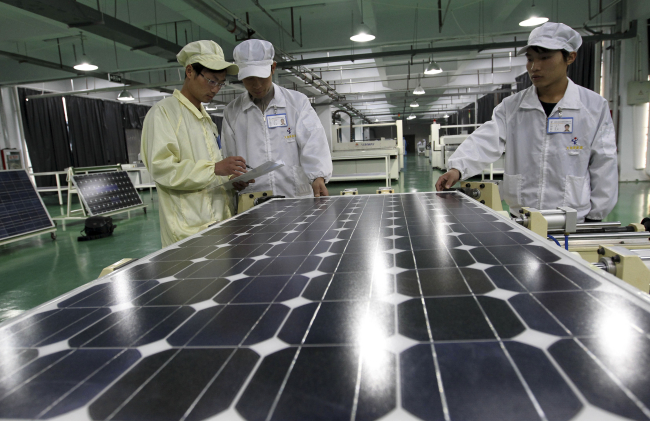 Chinese workers examine solar panels at a manufacturer of photovoltaic products in Huaibei, Anhui province in March 2012.   AP-Yonhap News