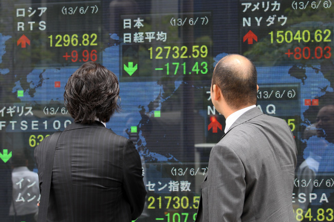 Pedestrian look at an electronic stock board displaying the Nikkei 225 Stock Average figure, top center, and other indices outside a securities firm in Tokyo, Japan, on Friday, June 7, 2013. Japanese Finance Minister Taro Aso said that the government won뭪 intervene in the currency market for now after the yen strengthened by the most in three years against the dollar. Photographer: Koichi Kamoshida/Bloomberg
Pedestrians look at an electronic stock board in Tokyo on Friday.   Bloomberg