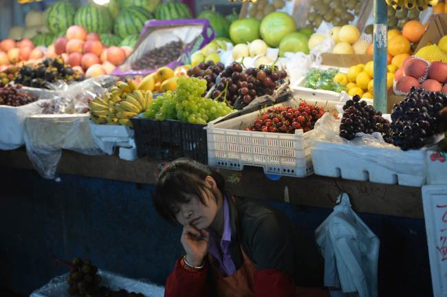 A fruit vendor takes a nap at a market in Shanghai on Sunday.    AFP-Yonhap News