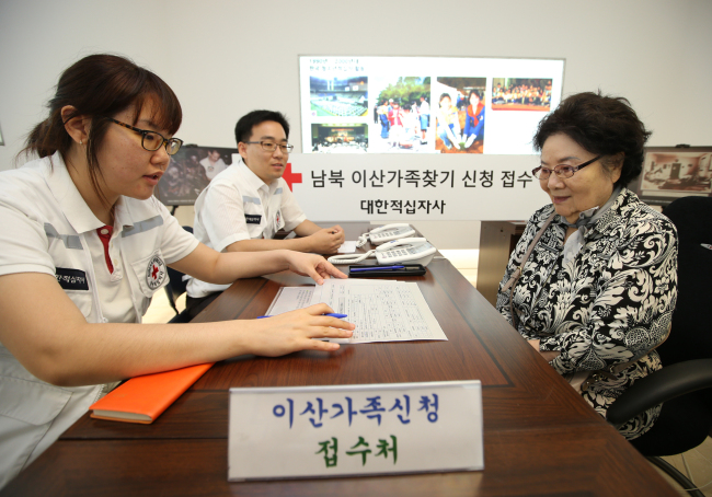 Korean Red Cross officials process an elderly woman’s application to meet with family members in North Korea in Seoul on Monday.   Yonhap News