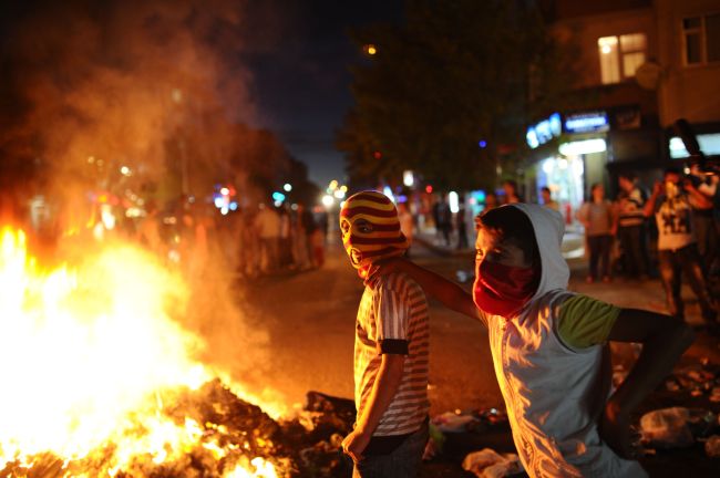 Turkish boys stand next to burning trash during a clash in Istanbul on Monday.   AFP-Yonhap News