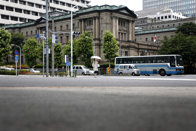 A pedestrian crosses the road in front of the Bank of Japan headquarters in Tokyo.    Bloomberg