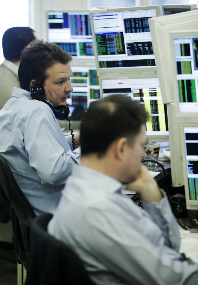 A stockbroker talks on the phone as he monitors financial data on computer screens at Shore Capital Group Ltd. brokerage in London.   Bloomberg