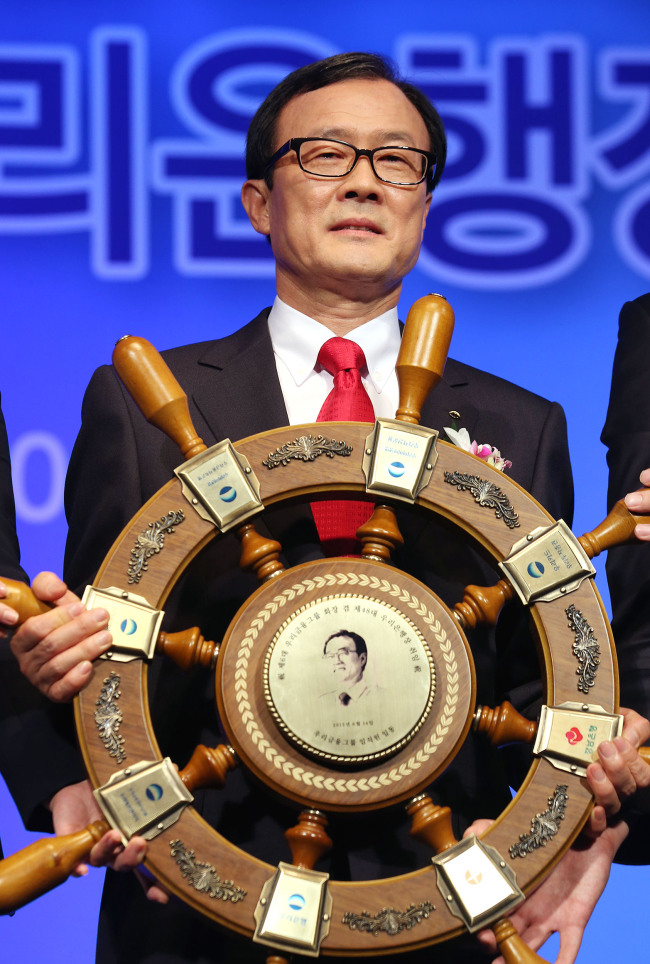 New Woori Financial Group chairman Lee Soon-woo poses with a memorial tablet presented by the group’s staff at his inaugural ceremony in Seoul on Friday.
Yonhap News