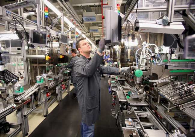 Employees work on Bosch’s CP4 diesel pumps as they move along the production line at the company’s Feuerbach factory near Stuttgart, Germany.   Robert Bosch Korea