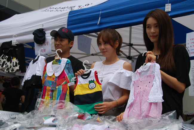 Singer Hong Kyung-min (left), actress Kim Jung-eun (center) and singer Ga Hee promote sales at the Social Welfare Society’s bazaar in aid of children waiting to be adopted in Seoul on Monday.    SWS