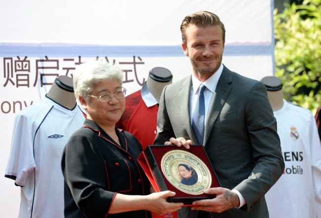Recently retired football player David Beckham (right) receives a souvenir during a donation ceremony in Beijing, China, Monday.   Xinhua-Yonhap News