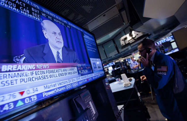 Traders work on the floor of the New York Stock Exchange as Ben Bernanke, chairman of the U.S. Federal Reserve, speaks on television in New York on Wednesday.    Bloomberg