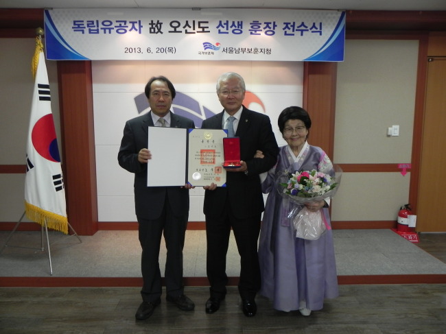 Herald Corp. senior adviser Sohn Myoung-won (center), a great grandson of independence fighter Oh Shin-do, receives a posthumous honor on her behalf from Yoon Doo-seoub (left), southern Seoul regional administrator of the Ministry of Patriots and Veterans Affairs, on Thursday.   Ministry of Patriots and Veterans Affairs