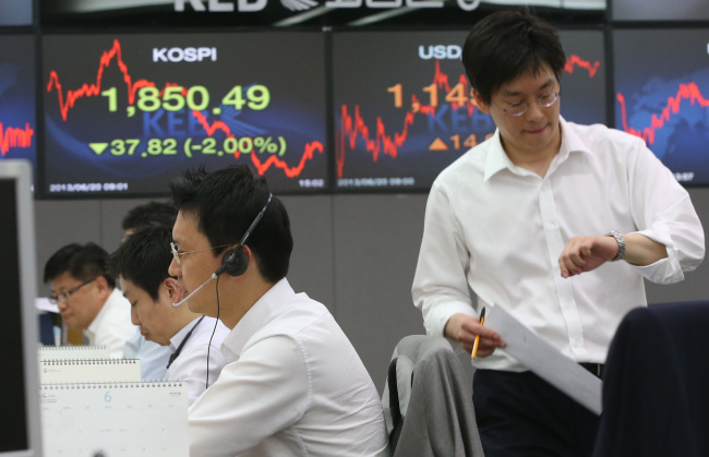 Traders at the headquarters of Korea Exchange Bank in Seoul look at financial indices on computers on Thursday.   Yonhap News