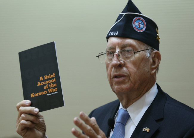 Larry Kinard, president of the Korean War Veterans Association, holds “A Brief Account of the Korean War” published to educate U.S. students about the war during his lecture at the Korea Military Academy in Seoul on Friday.
Yonhap News