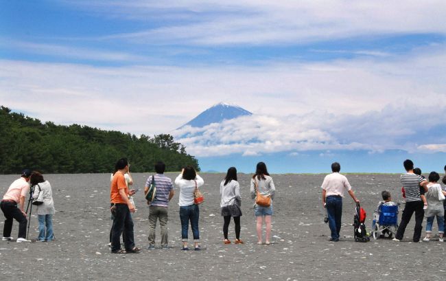 Sightseers enjoy Mount Fuji seen behind the clouds as UNESCO granted World Heritage status to Japan’s Mount Fuji at Fujiyoshida city in Shizuoka prefecture on Saturday.   AFP-Yonhap News