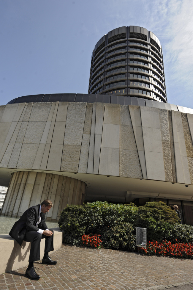 A businessman sits in front of the Bank for International Settlements in Basel, Switzerland.   Bloomberg