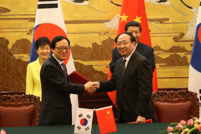김용환(앞줄 왼쪽) 한국수출입은행장과 리뤄구 중국수출입은행장이 지난 27일 오후 중국 베이징 인민대회당에서 ‘한ㆍ중 기업의 제3국 공동 진출 지원을 위한 상호리스크 참여 약정서’에 서명한 뒤 악수하고 있다. [베이징=연합뉴스]