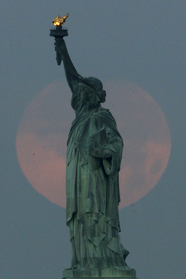 A supermoon sets behind the Statue of Liberty in New York on Sunday.   AP-Yonhap News