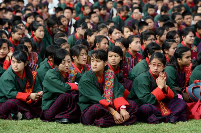 Schoolgirls sit in a field during a cultural event to celebrate the birthday of Bhutan’s fourth king at a local school in Thimphu on June 2.   AFP-Yonhap News
