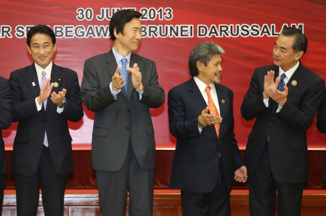 South Korean Foreign Minister Yun Byung-se (second from left) claps while attending a ceremony of the ASEAN Plus Three Foreign Minister Meeting at the ASEAN Regional Forum in Bandar Seri Begawan, Brunei Darussalam, Sunday. On the left is Japanese Foreign Minister Fumio Kishida and on the far right is Chinese Foreign Minister Wang Yi.   Yonhap News