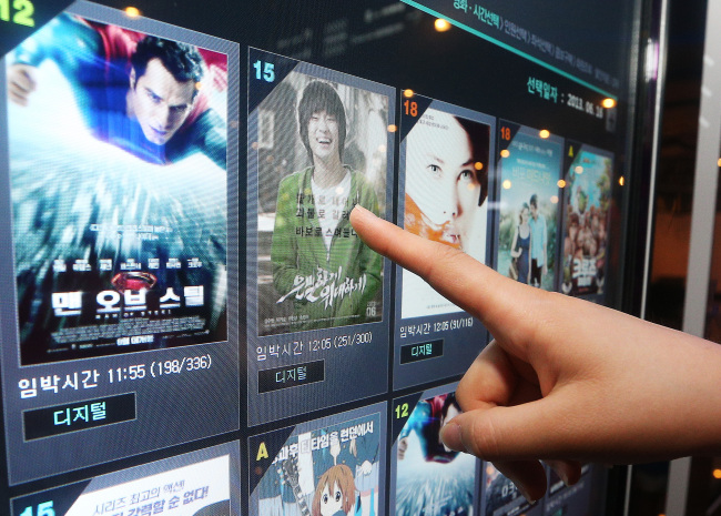 A moviegoer buys a ticket for “Secretly Greatly” in Samseong-dong on June 16. The movie drew more than 5 million viewers in its first 12 days of release.   Yonhap News