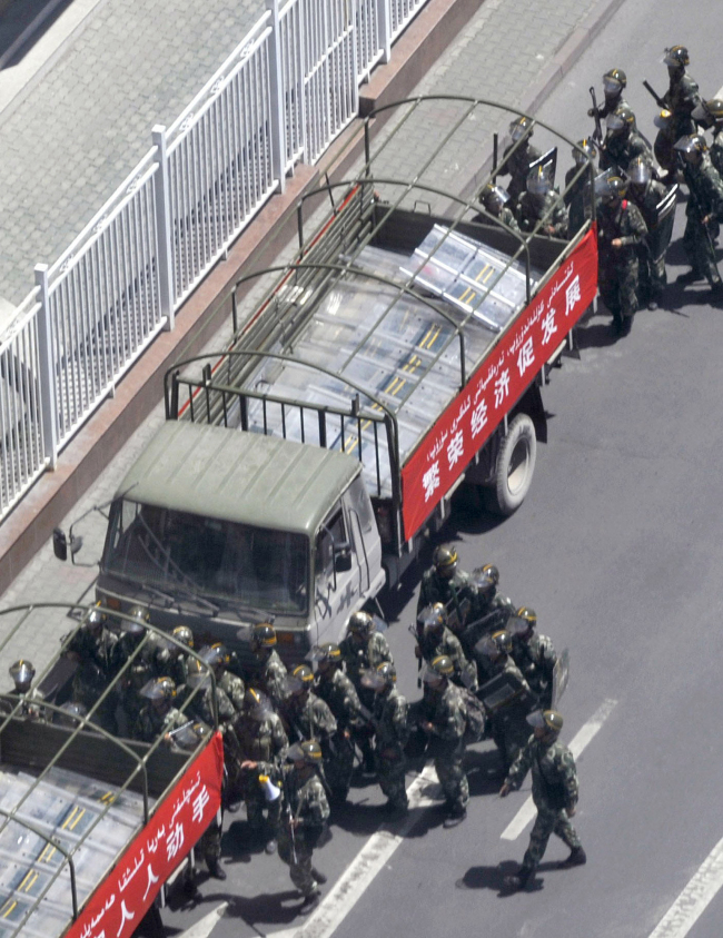 Armed police officers board trucks to patrol in Urumqi, western China’s Xinjiang province, Sunday.   AP-Yonhap News