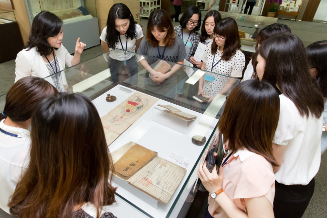 Students look at the original copy of “Dongui Bogam,” a book about traditional Korean medicine published 400 years ago, at the National Museum of Korea on Monday. Yonhap News
