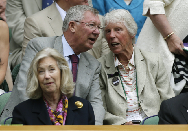 Former Manchester United manager Alex Ferguson (left) and former Wimbledon Women’s singles champion Ann Jones take their seats at Wimbledon, London, Wednesday.   AP-Yonhap News