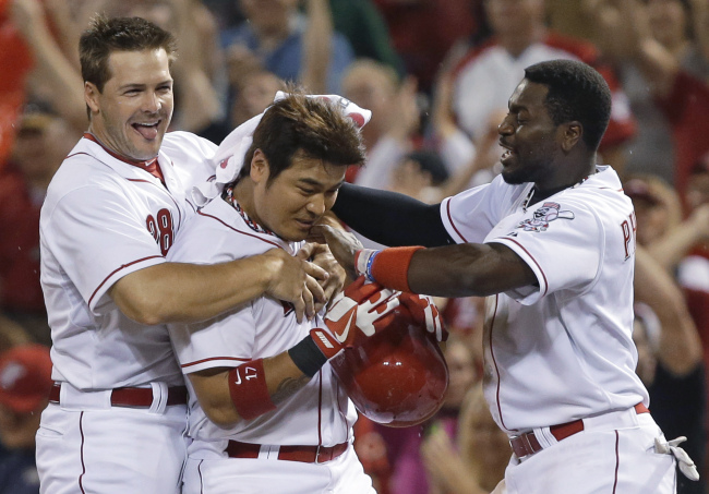 Cincinnati Reds’ Choo Shin-soo (center) is congratulated by left fielder Chris Heisey (left) and second baseman Brandon Phillips after he drove in the winning run in the 11th inning of a baseball game against the San Francisco Giants in Cincinnati on Wednesday.   AP-Yonhap News