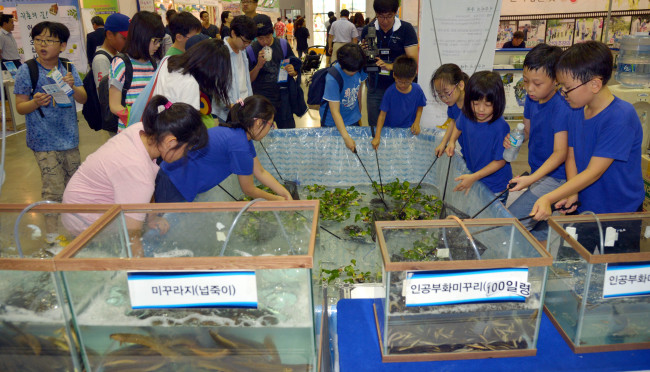 Kids try catching mudfish during the rural festival at KINTEX in Goyang, Gyeonggi Province.   Kim Myung-sub/The Korea Herald