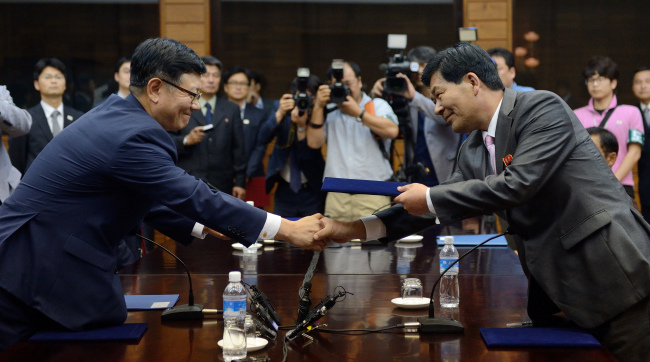 South Korea’s chief delegate Suh Ho (left) and his North Korean counterpart Park Chol-su exchange documents of an agreement on the Gaeseong industrial complex at the close of 16-hour talks at Panmunjeom on Sunday.   Joint Press Corps